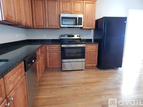 A kitchen with wooden cabinets and black countertops.