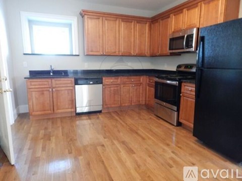 A kitchen with wooden cabinets and black appliances.