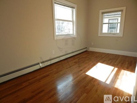 A room with wooden floors and two windows.