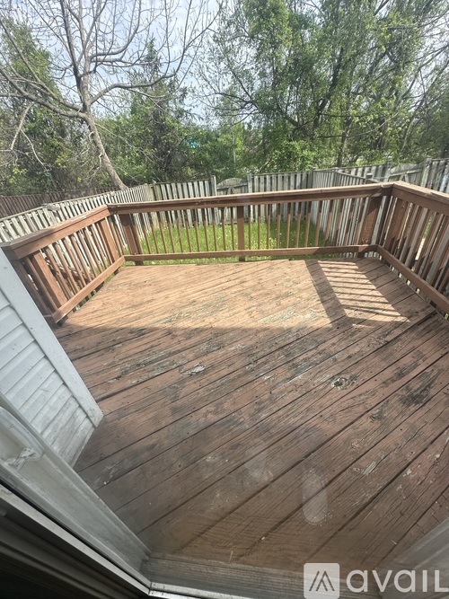 A wooden deck with a railing and a view of trees in the background.