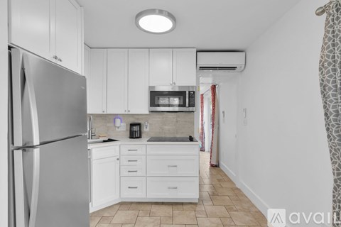 A kitchen with white cabinets and a refrigerator.