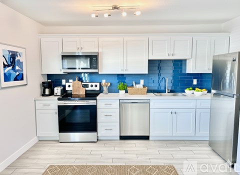 A kitchen with white cabinets and a blue backsplash.