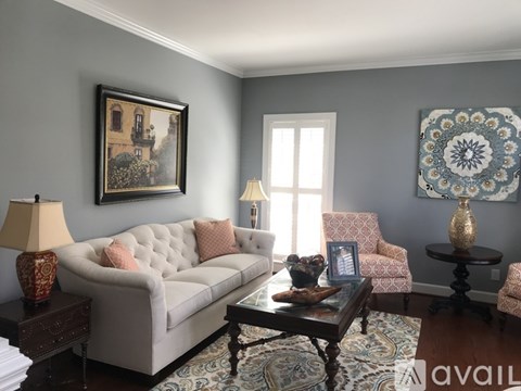 A living room with a couch, chair, and a painting on the wall.