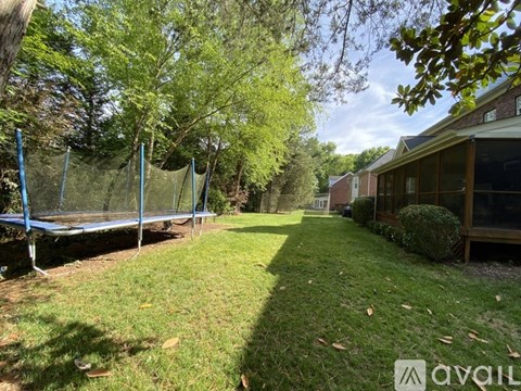 A backyard with a trampoline and a house.