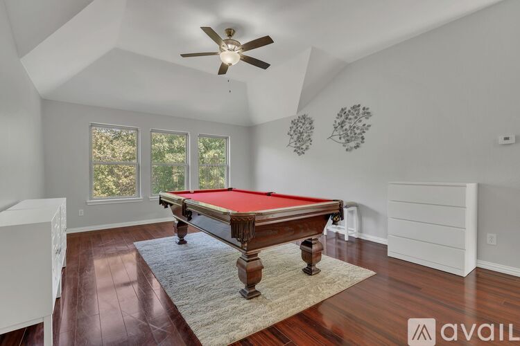 A pool table is in the middle of a room with a ceiling fan.