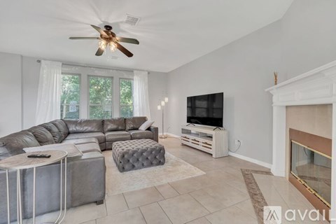 A living room with a grey sofa and a television on a wooden stand.