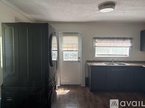 A kitchen with a black refrigerator and a white door.