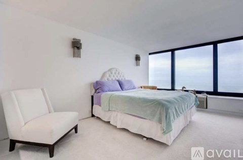A bedroom with a bed, chair, and window.