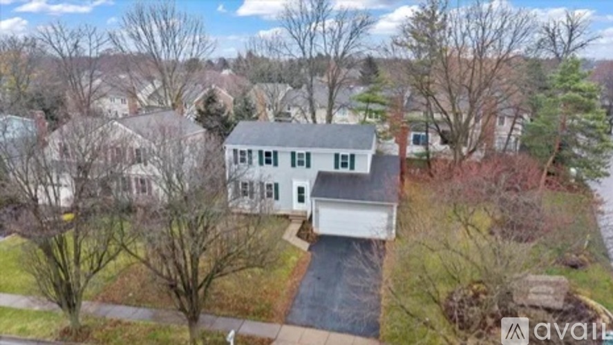 A house with a driveway and trees in the background.