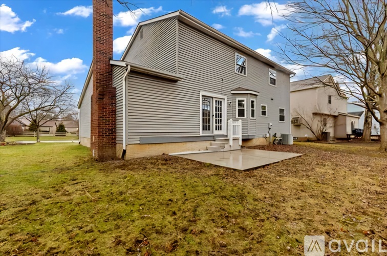 A house with a grey exterior and a red brick chimney is for sale.