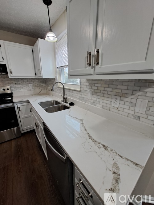 A kitchen with white cabinets and a marble countertop.