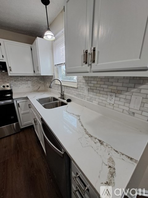 A kitchen with white cabinets and a marble countertop.