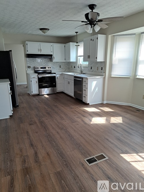 A kitchen with white cabinets and a black refrigerator.