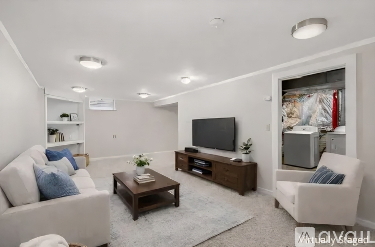 A living room with a white couch, a coffee table, and a television.