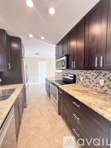 A kitchen with dark brown cabinets and a granite countertop.
