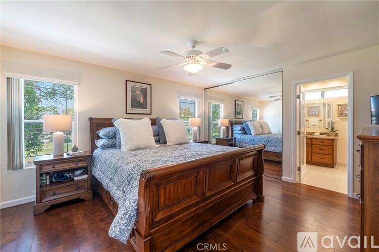 A bedroom with a large bed, a ceiling fan, and a nightstand with a lamp.