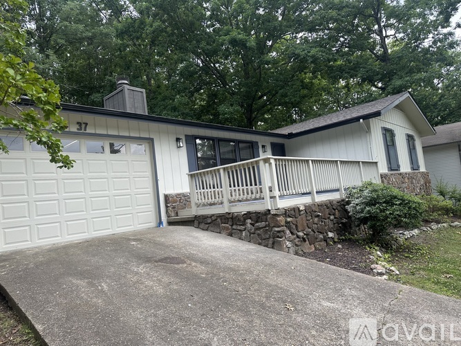A house with a garage and a porch is surrounded by trees.