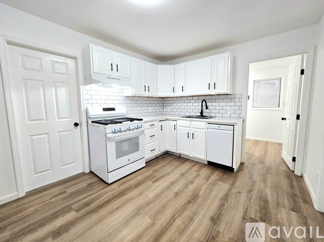 A kitchen with white cabinets and a white stove top oven.