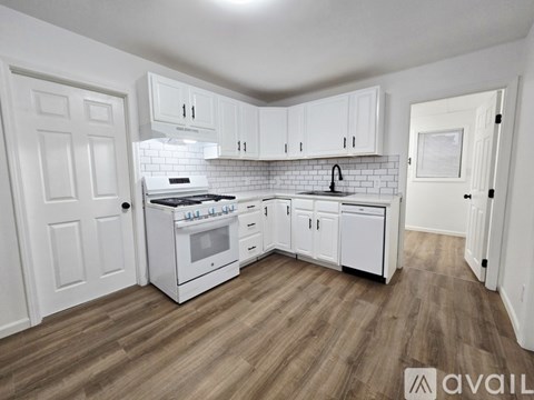 A kitchen with white cabinets and a white stove top oven.