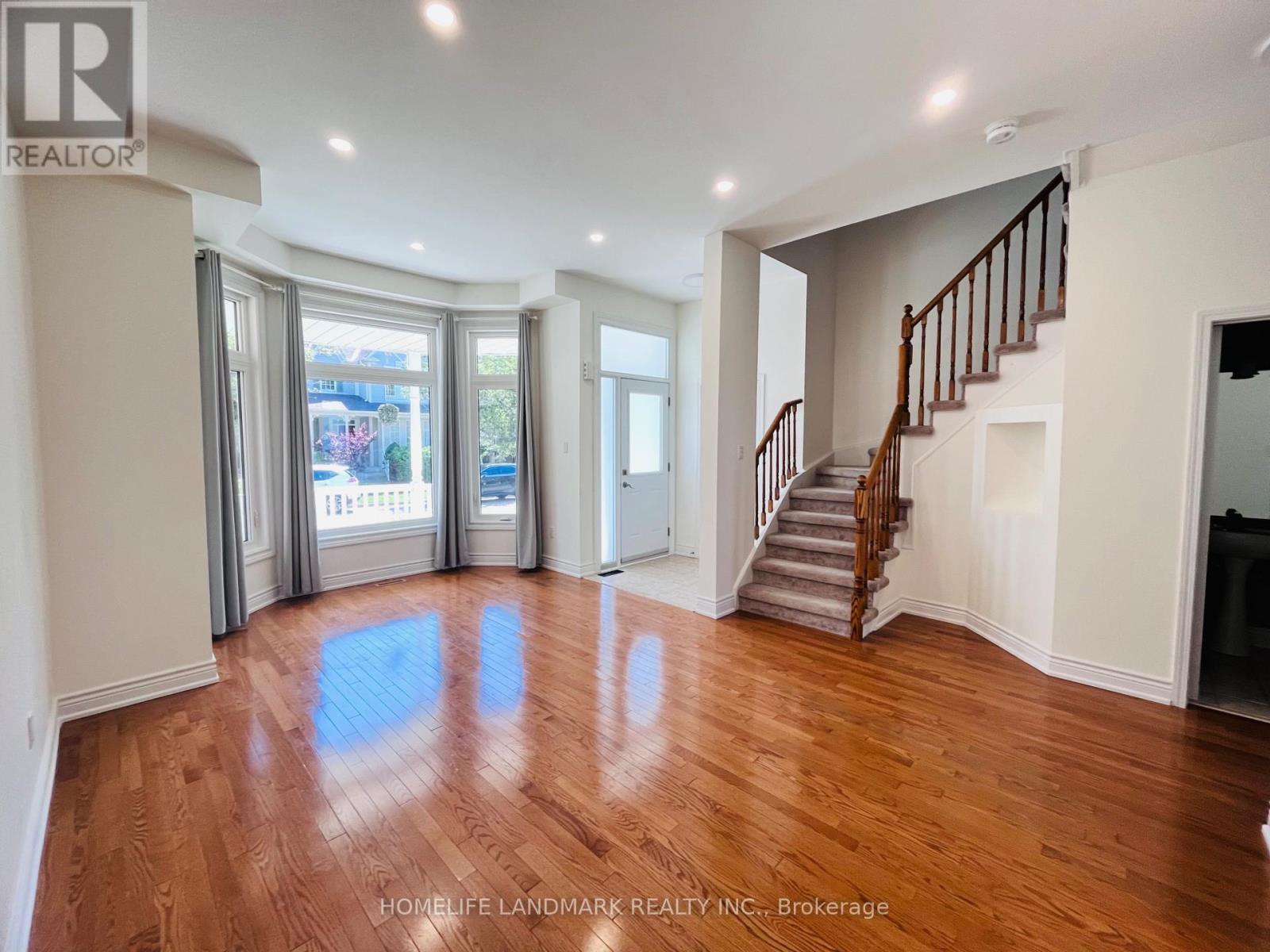 A spacious room with wooden floors and a staircase.
