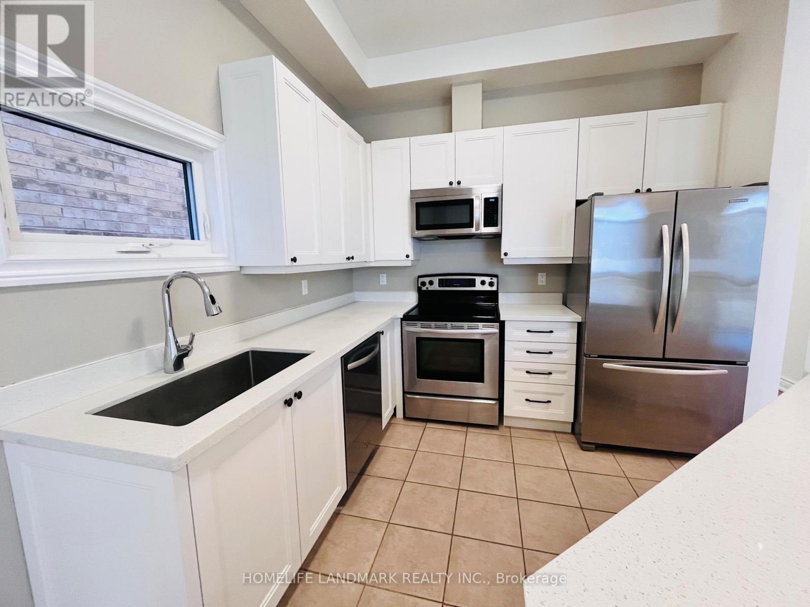 A kitchen with white cabinets and a stainless steel refrigerator.