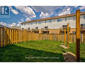 A wooden fence surrounds a grassy area in front of a building.