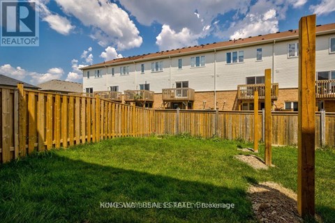 A wooden fence surrounds a grassy area in front of a building.