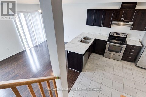 A modern kitchen with dark wood cabinets and stainless steel appliances.