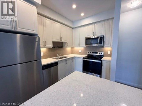 A kitchen with a refrigerator, microwave, oven, and sink.