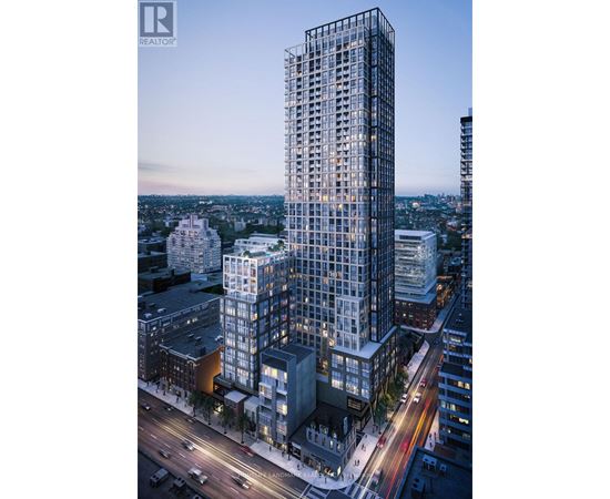A tall building with many windows is lit up at dusk.