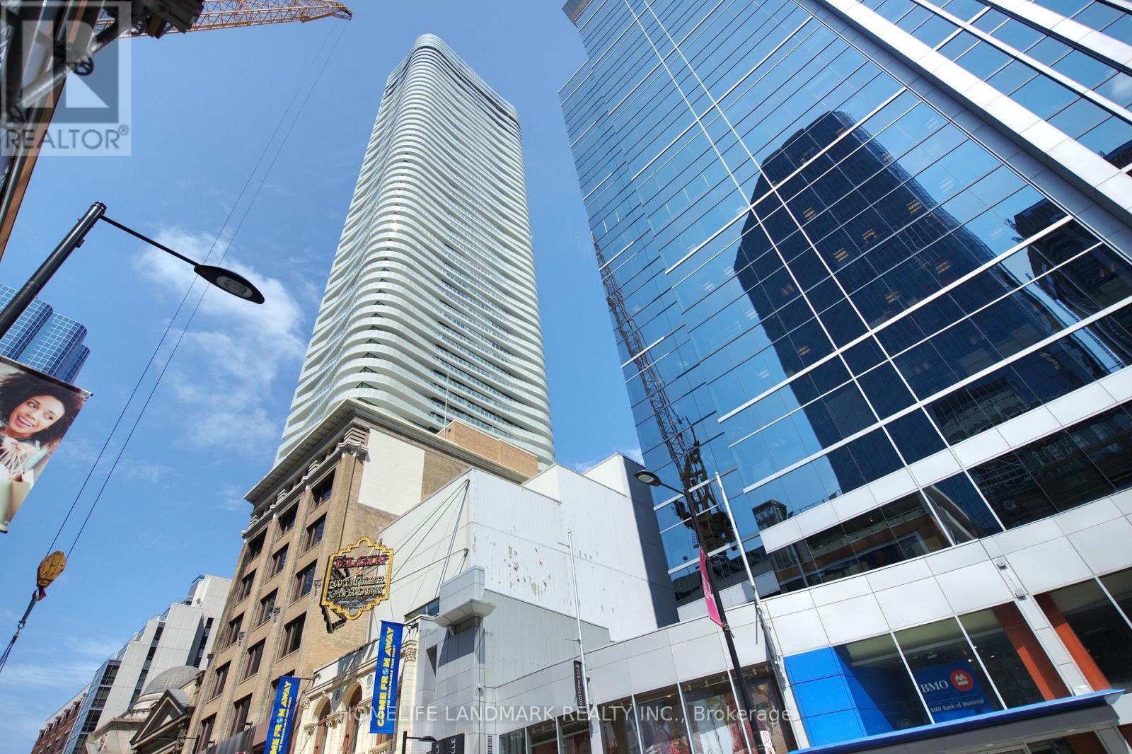 A tall building with a curved top stands in front of a modern glass building.