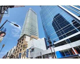 A tall building with a curved top stands in front of a modern glass building.