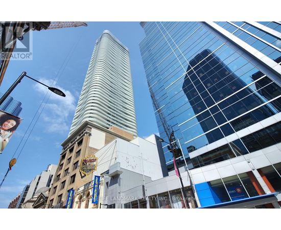 A tall building with a curved top stands in front of a modern glass building.