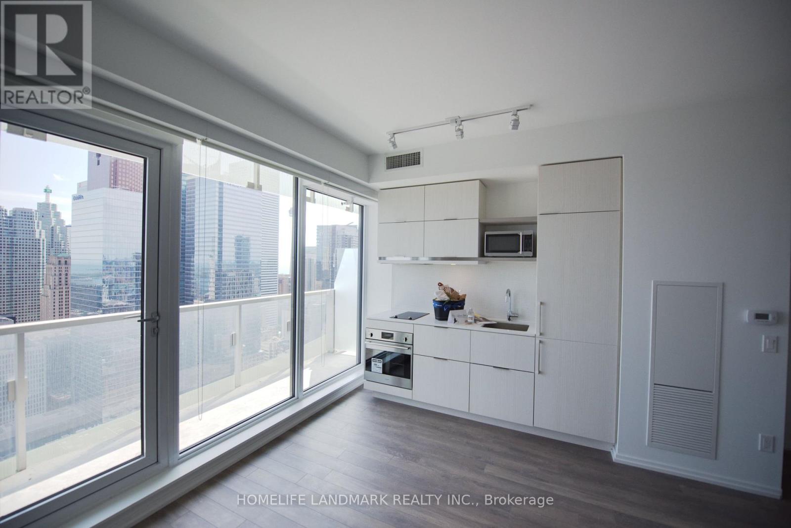 A modern kitchen with white cabinets and a view of the city.