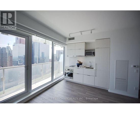 A modern kitchen with white cabinets and a view of the city.