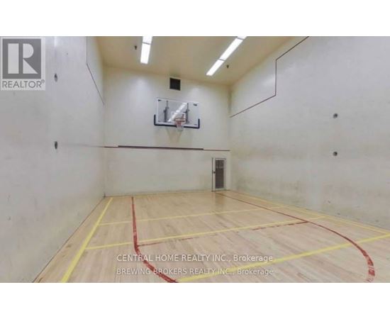 A gym with a basketball hoop and a wooden floor.