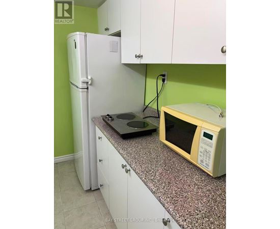 A kitchen with a white fridge and a microwave on a granite counter.