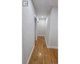 A long hallway with wood floors and white walls.