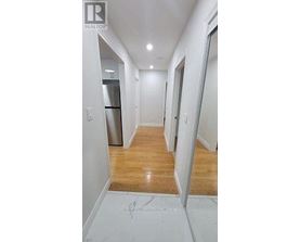 A hallway with a wooden floor and white walls.