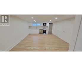 A spacious empty room with wooden flooring and white walls.