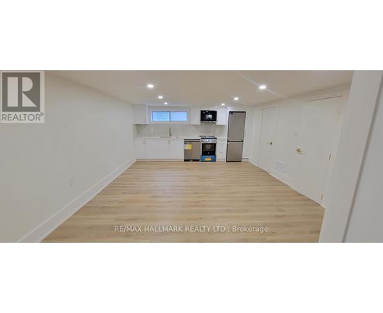 A spacious empty room with wooden flooring and white walls.