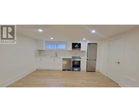 A white kitchen with a refrigerator, microwave, and oven.