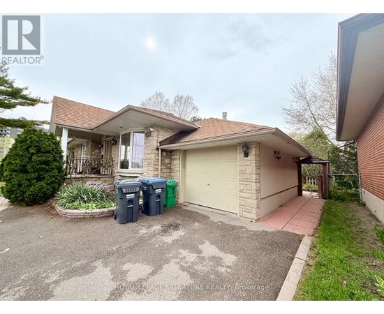 A house with a driveway and two trash bins in front.