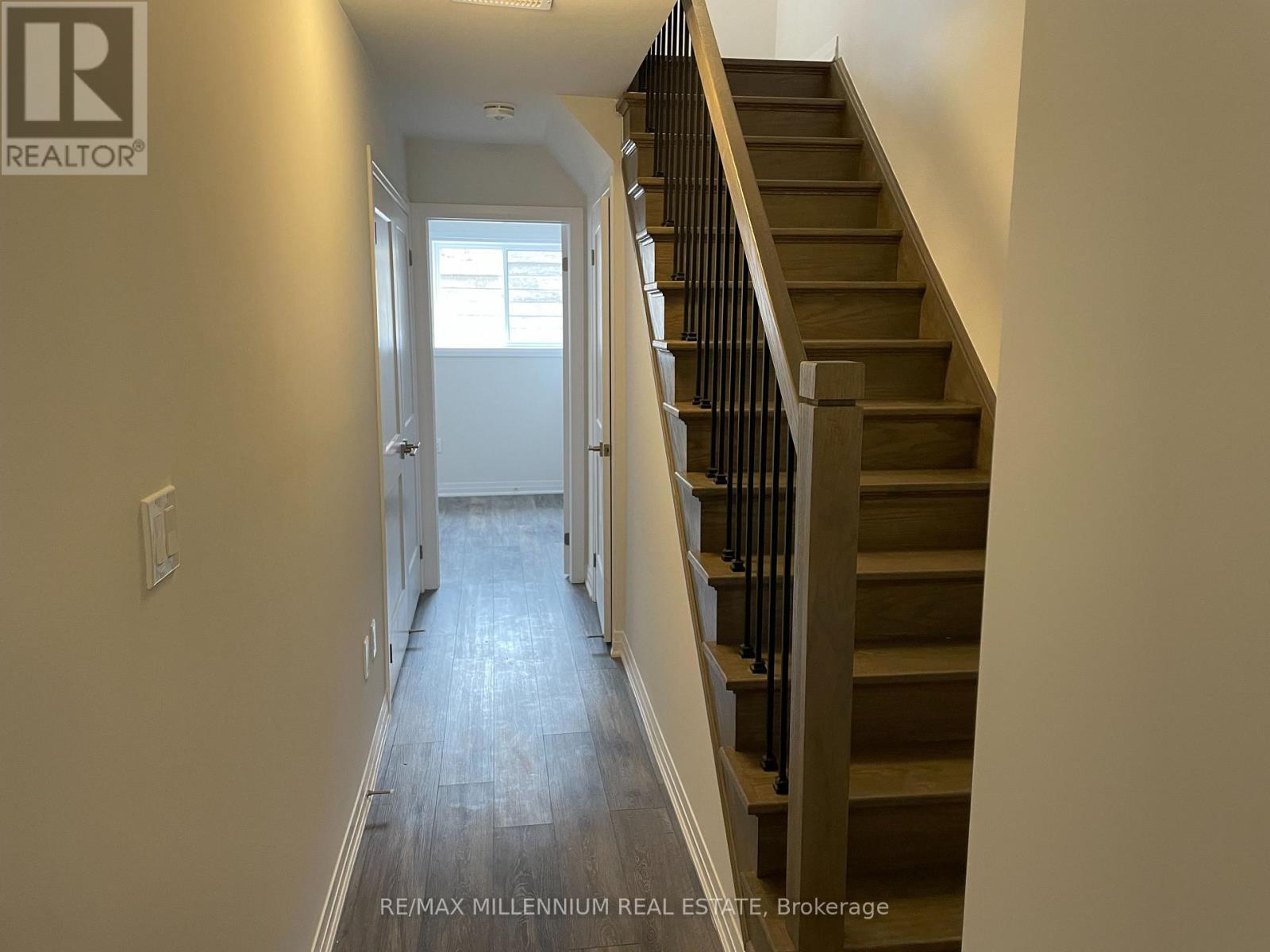 A hallway with a staircase and a doorway leading to another room.