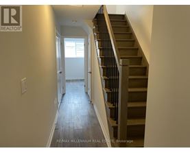 A hallway with a staircase and a doorway leading to another room.