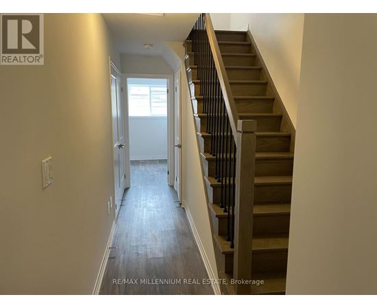 A hallway with a staircase and a doorway leading to another room.