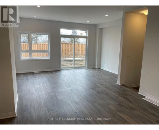 A spacious room with wooden flooring and a view of a fence through a window.
