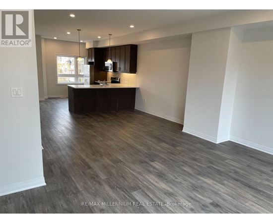 A spacious room with a wooden floor and a kitchen area with a counter and cabinets.