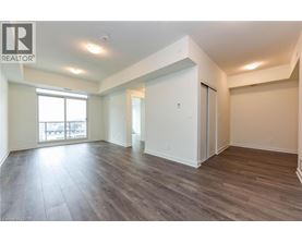 A spacious room with wood flooring and white walls.