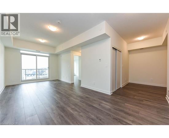 A spacious room with wood flooring and white walls.